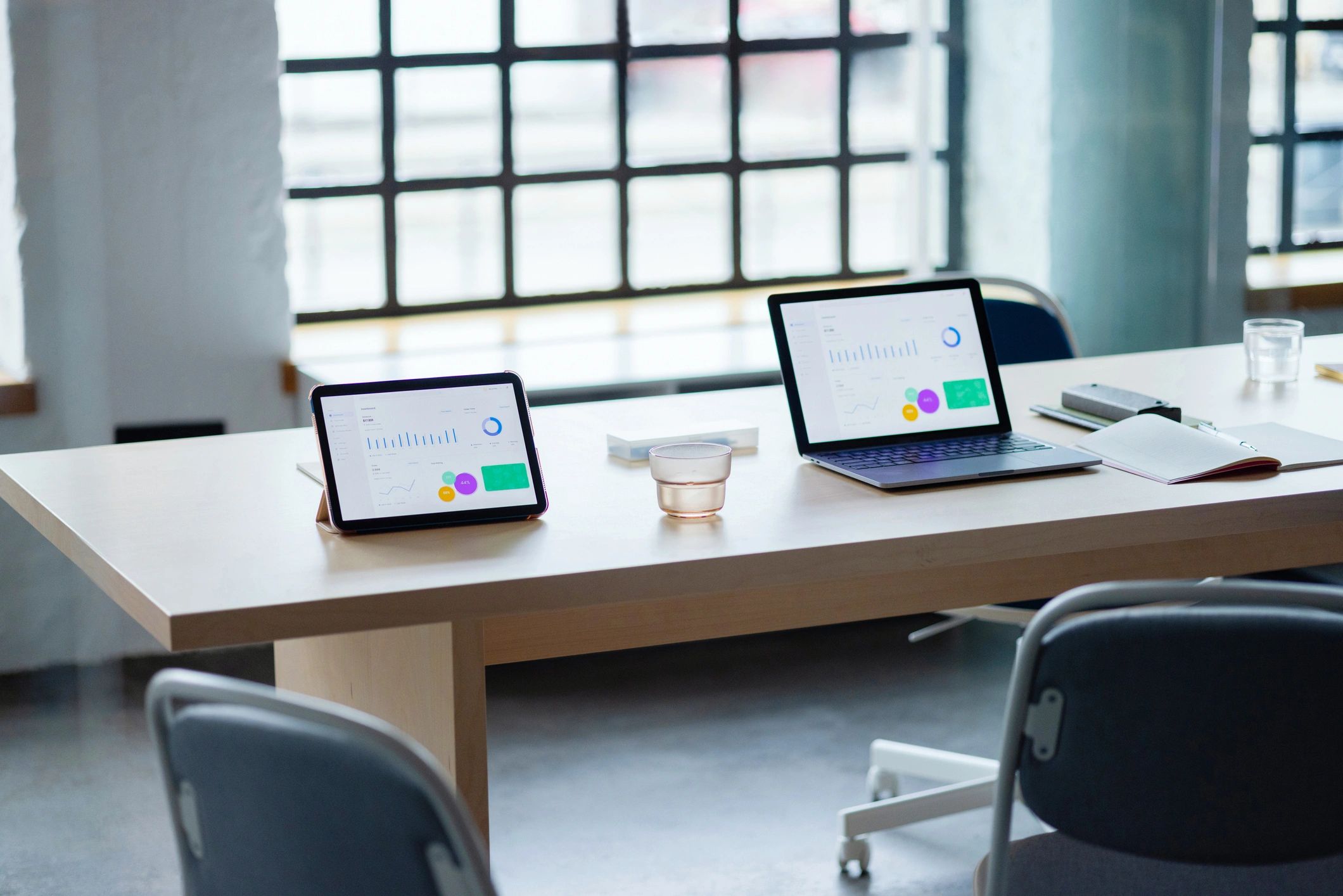 Modern business workspace with laptop and tablet displaying charts